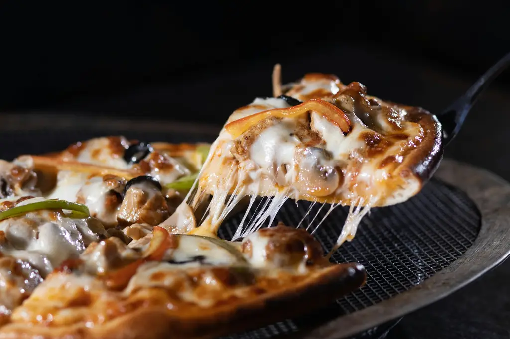 Pizzastück mit langen Käsefäden wird mit dem Pizzaschieber angehoben