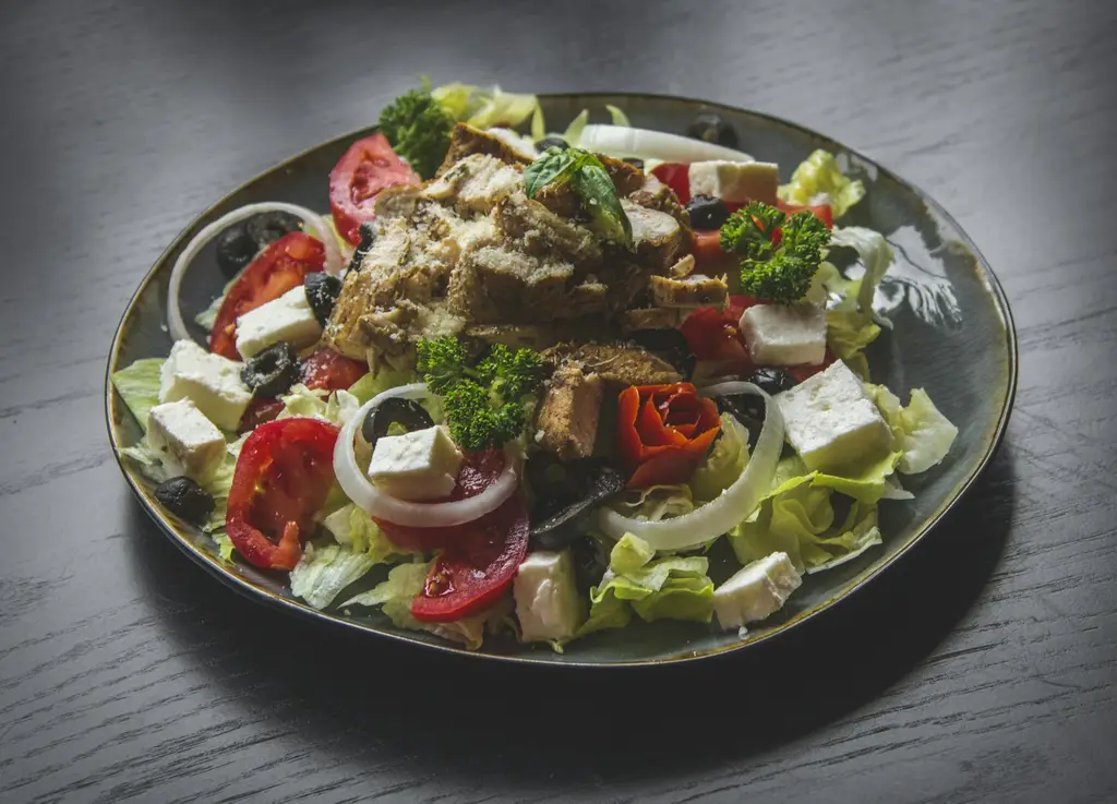 Bunter Salat mit Tomaten, Gurken, Zwiebeln und Feta in einer dunklen Schale