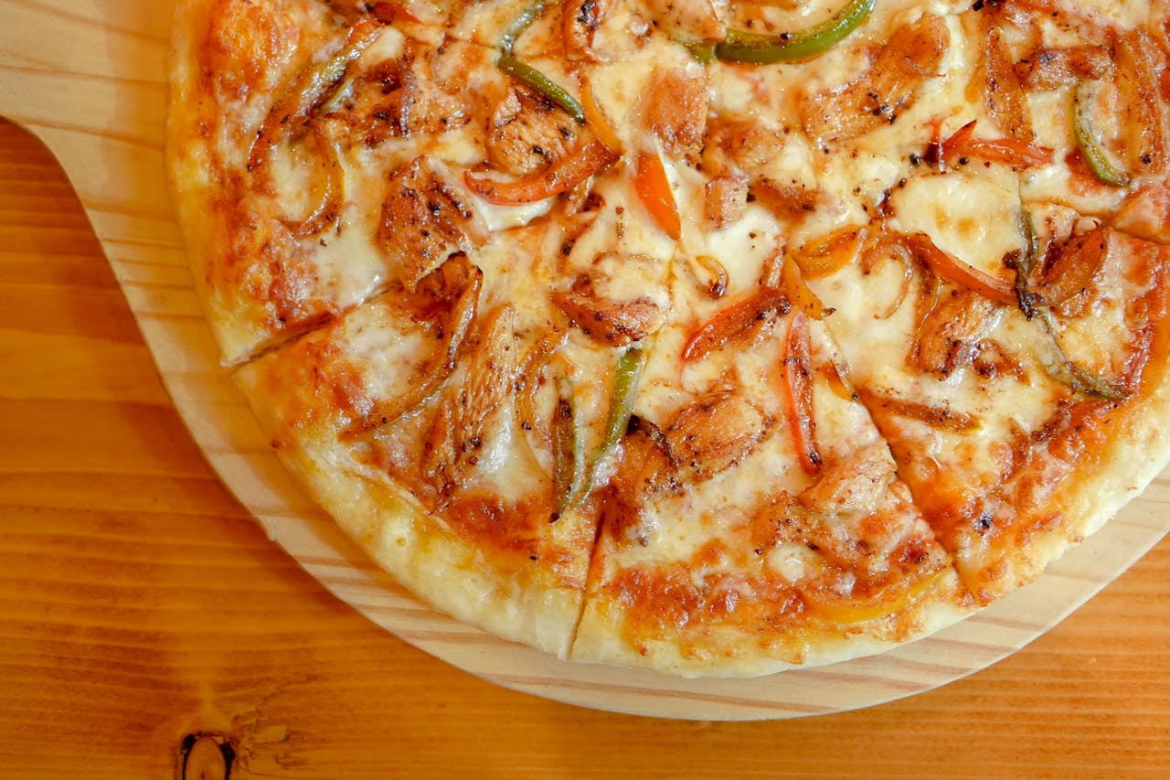 Delicious close-up view of a hot chicken pizza topped with onions and peppers.